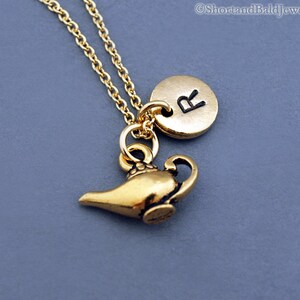 Puede incluir: Un collar de oro con un dije de una l&aacute;mpara de genio y un dije redondo con la letra "R" en &eacute;l.