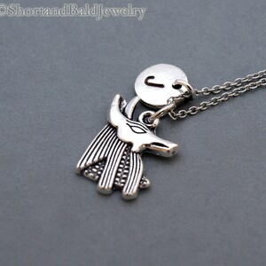 May include: Silver necklace with a charm of an Anubis head and a round charm with the letter J.
