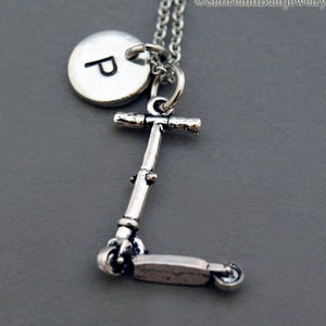 May include: Silver necklace with a scooter charm and a personalized initial disc. The initial disc is engraved with the letter "P".