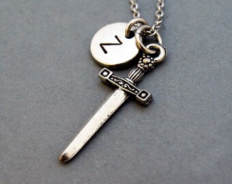 May include: Silver necklace with a sword charm and a round charm with the letter "Z" engraved on it.
