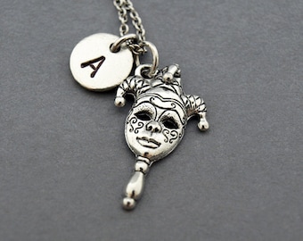 May include: Silver necklace with a jester mask charm and a round charm with the letter A.
