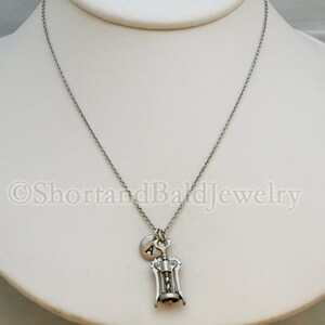 May include: A silver necklace with a corkscrew charm and a small silver charm with the letter A.