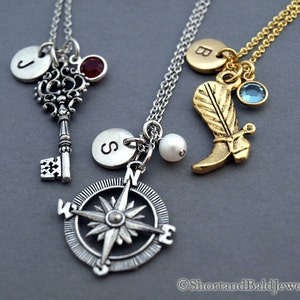 May include: Three silver necklaces with charms. The first necklace has a silver key charm, a silver initial charm with the letter "J", and a red gemstone. The second necklace has a silver compass charm, a silver initial charm with the letter "S", and a white pearl. The third necklace has a gold boot charm, a gold initial charm with the letter "B", and a blue gemstone.