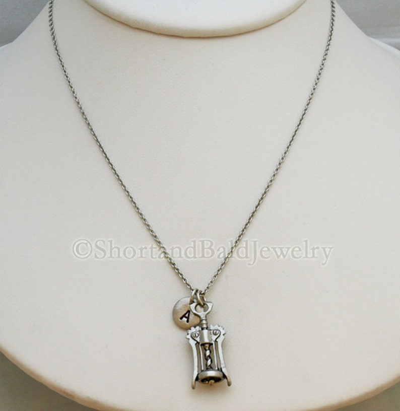 May include: A silver necklace with a corkscrew charm and a small silver disc charm with the letter 'A' on it.