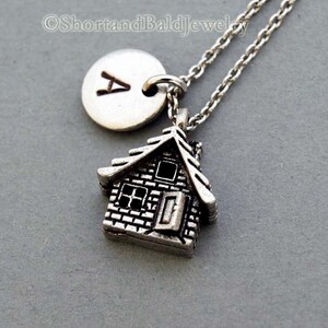 May include: Silver necklace with a small house charm and a round charm with the letter A engraved on it.