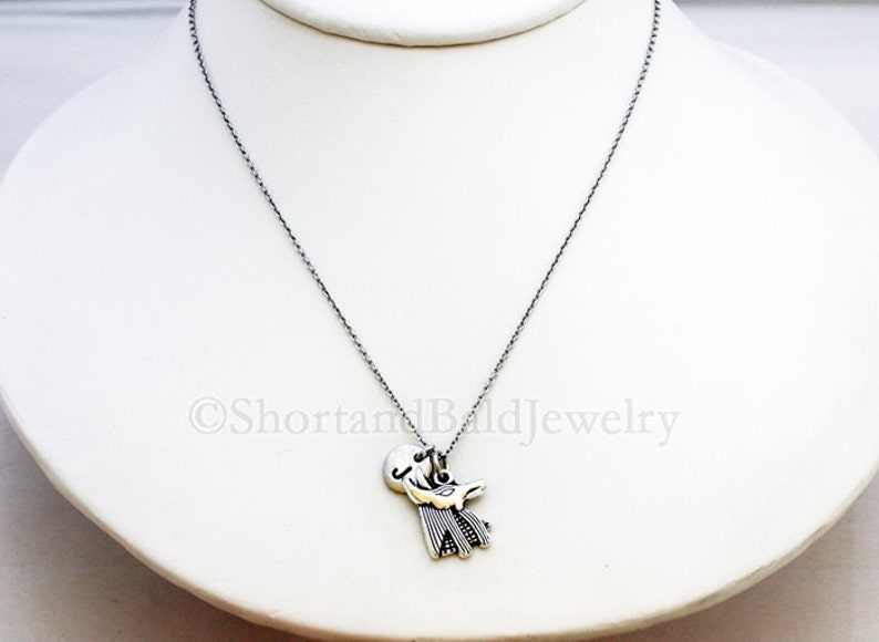 May include: A silver chain necklace with a silver pendant featuring a stylized bird design.