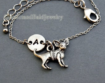 May include: Silver charm bracelet with a small silver chihuahua charm and a round silver charm with the letter "A" engraved on it.