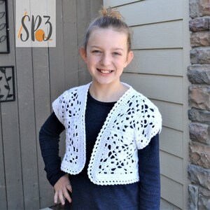 Peut inclure: Un cardigan court en crochet blanc avec un motif ajouré. Le cardigan a des manches courtes et un col en V.