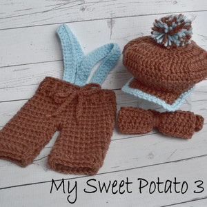 May include: A brown and blue crochet outfit for a baby, including shorts with suspenders, a hat with a pom-pom, a bow tie, and a small scarf. The text "My Sweet Potato 3" is written in black cursive font.