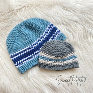 May include: Two crocheted hats with striped patterns. The larger hat is blue with white and blue stripes. The smaller hat is gray with white and beige stripes.
