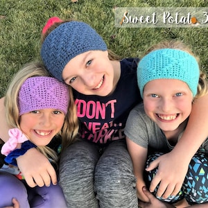 May include: Three girls wearing crocheted headbands in purple, blue, and turquoise. The girls are smiling and hugging each other. The headband is a crochet ear warmer.