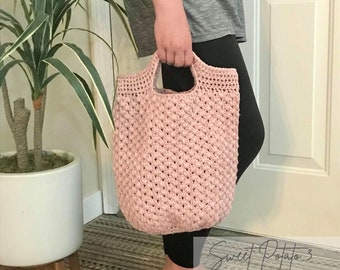May include: A pink crocheted tote bag with a single handle. The bag is made with a textured stitch and has a slightly slouchy shape.