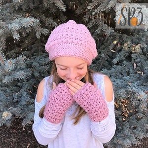 May include: A pink crocheted beret and fingerless gloves set. The beret has a textured stitch pattern and the gloves have a similar stitch pattern.