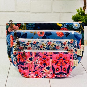 Pode incluir: Conjunto de quatro bolsas com fecho de correr de diferentes tamanhos com padrão floral. As bolsas são azul marinho, azul claro, branco e rosa. A bolsa mais pequena tem um fundo rosa com flores vermelhas e pássaros brancos. As bolsas estão empilhadas umas sobre as outras.