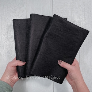 May include: Three black felt sheets stacked on top of each other. The felt is soft and has a slightly fuzzy texture.