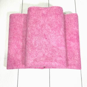 May include: Three pink fabric squares, possibly for crafting or quilting.