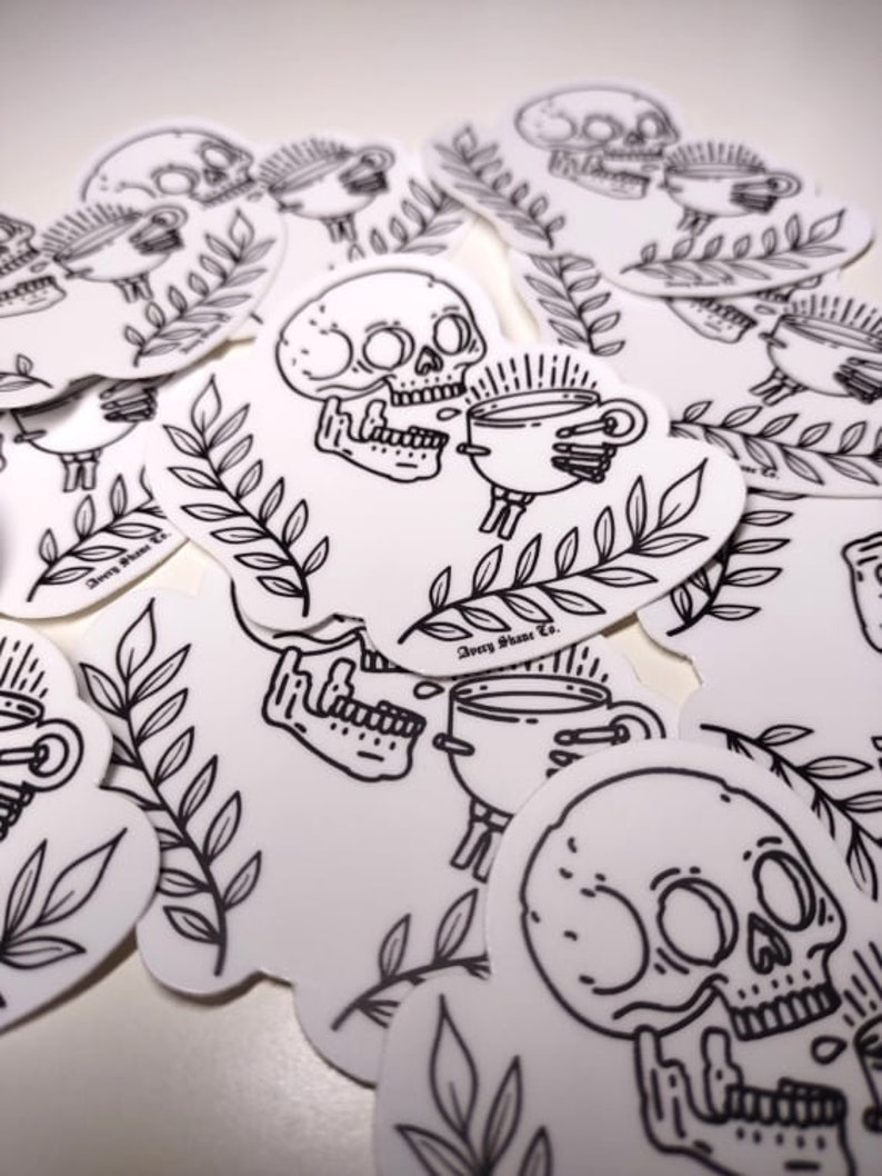 May include: A set of black and white stickers featuring a skull holding a cup of coffee. The stickers have a simple line art style and include the text "Avery Stone Co.".