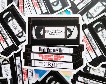 May include: A stack of VHS tapes with titles including "Practical Magic", "Death Becomes Her", "The Rocky Horror Picture Show", and "The Craft".