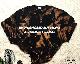 May include: Black bleached t-shirt with the text "Undiagnosed but I have a strong feeling" in white.
