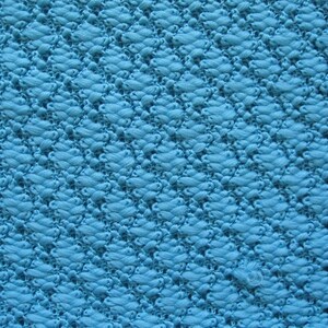 May include: A close-up of a blue textured fabric with a diamond pattern. The fabric is woven with a raised texture.