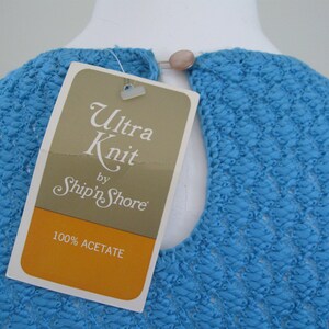 May include: A blue knit top with a white tag that reads "Ultra Knit by Ship'n Shore" and "100% Acetate".