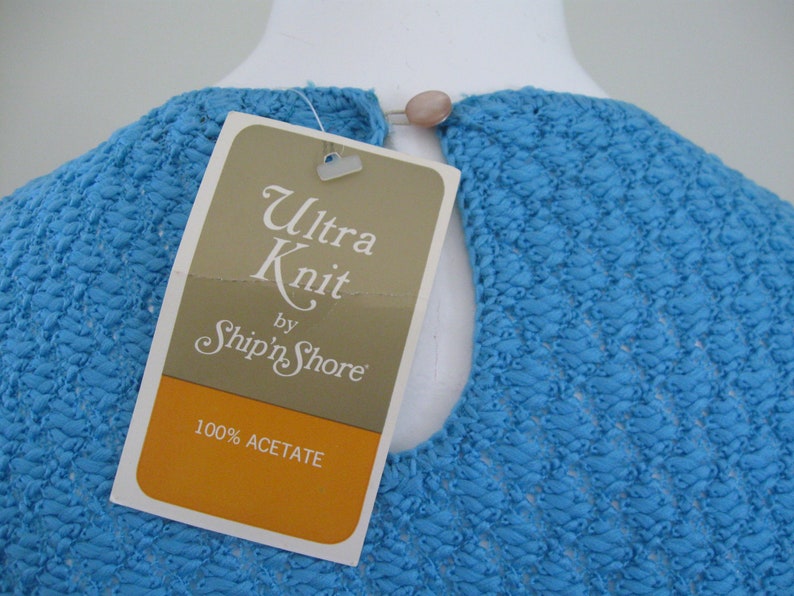 May include: A blue knit top with a white tag that reads "Ultra Knit by Ship'n Shore" and "100% Acetate".