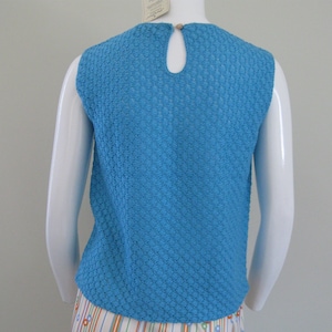 May include: A sleeveless, blue, textured knit top with a round neckline. The top has a keyhole opening in the back.