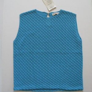 May include: A sleeveless blue knitted top with a diamond pattern. The top has a round neckline and a zipper in the back.