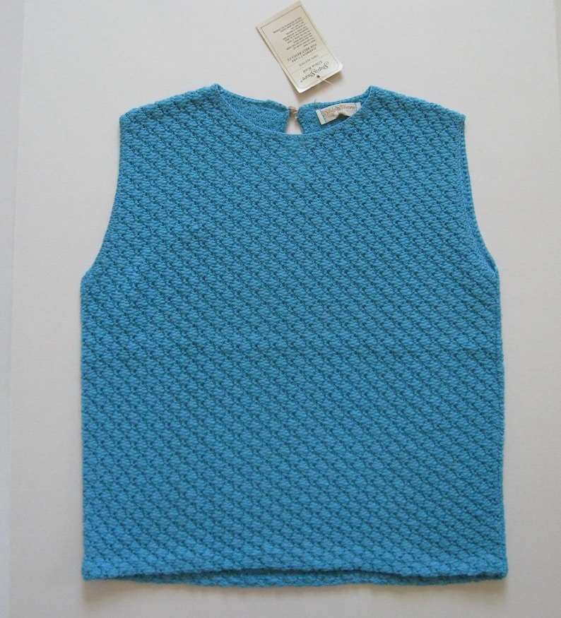 May include: A sleeveless blue knitted top with a diamond pattern. The top has a round neckline and a zipper in the back.