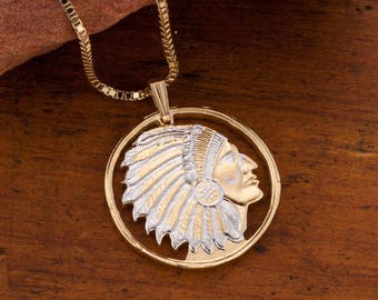 May include: Gold chain necklace with a round pendant featuring a profile of a Native American wearing a headdress. The pendant is made of two-toned metal, with gold and silver accents.