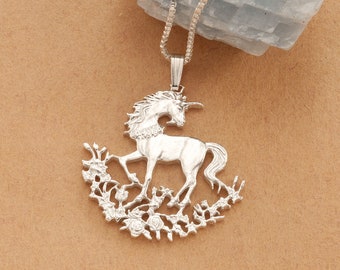 May include: Silver pendant necklace featuring a detailed unicorn design with a floral border. The unicorn is standing on its hind legs with its head turned to the side. The pendant is on a brown background.
