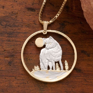 May include: A gold necklace with a round pendant featuring a silver wolf silhouette against a moon and trees. The pendant is made from a cut coin.