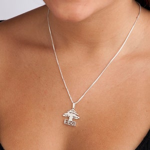 May include: A silver necklace with a pendant shaped like a cedar tree with the word "Lebanon" written on a banner below the tree.