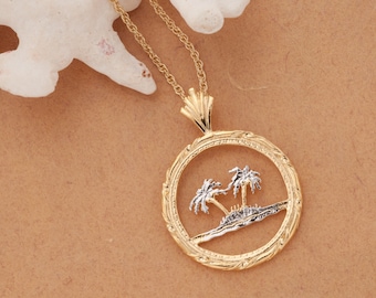 May include: A gold necklace with a pendant featuring two palm trees on a small island, all within a circular frame with a textured design.