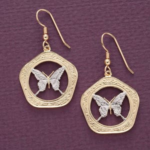 May include: Gold tone earrings featuring a silver butterfly design within a circular frame. The earrings have a delicate, intricate design.