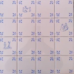 May include: A white tiled wall with a blue floral pattern. The tiles feature hand-painted scenes of people in traditional clothing. One tile shows a group of people playing music, while another tile shows a group of people dancing.