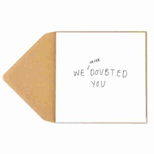May include: A white card with a brown envelope. The card has the text "Never We'Doubted You" written on it.