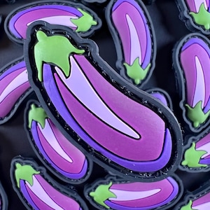 Puede incluir: Un primer plano de un parche de berenjenas moradas y verdes. La berenjena es una verdura popular y se usa a menudo en la cocina.