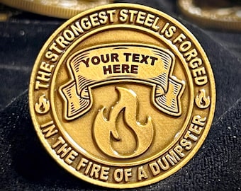 May include: Gold-colored metal coin with the text "The Strongest Steel Is Forged In The Fire Of A Dumpster" and a banner that says "Your Text Here" above a stylized flame.