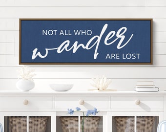 May include: A navy blue framed canvas wall art with white text that reads "Not all who wander are lost".