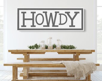 May include: A white sign with black lettering that reads "HOWDY" hanging on a white wall above a wooden table and benches.