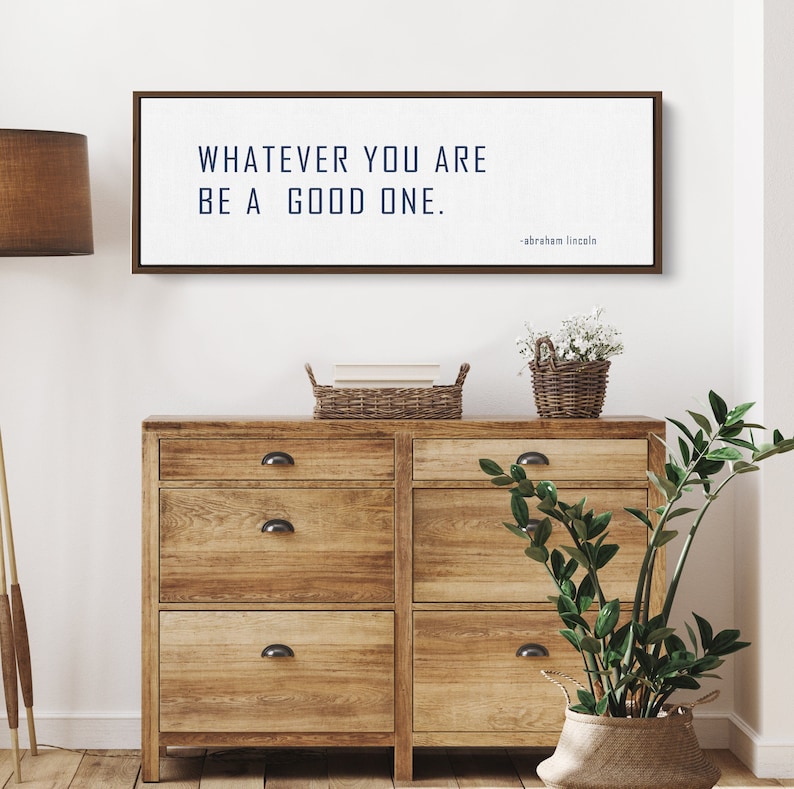 May include: A brown wooden framed print with the quote "Whatever you are, be a good one." attributed to Abraham Lincoln.