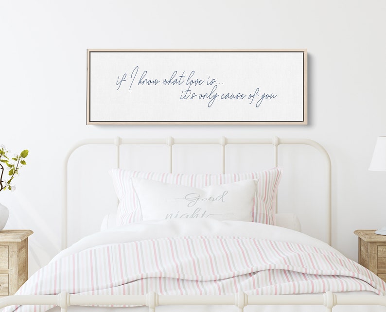 Pu&ograve; includere: Una stampa su tela bianca con una citazione in corsivo blu che recita "if I know what love is... it's only cause of you". La stampa &egrave; appesa sopra un letto bianco con biancheria da letto a righe rosa e bianche.