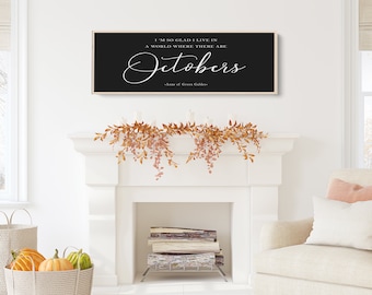 May include: A black and white sign with the quote "I'm so glad I live in a world where there are Octobers - Anne of Green Gables" hanging above a white fireplace mantel decorated with fall foliage.