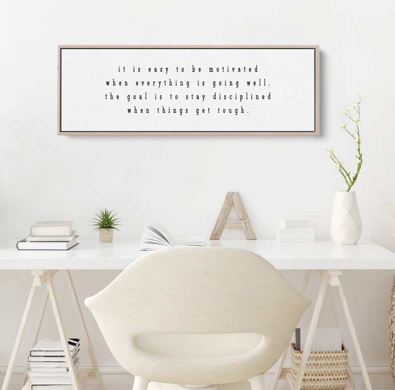 K&ouml;nnte beinhalten: Ein gerahmter Druck mit einem motivierenden Zitat in schwarzer Schrift auf wei&szlig;em Hintergrund. Das Zitat lautet: "it is easy to be motivated when everything is going well. the goal is to stay disciplined when things get tough."