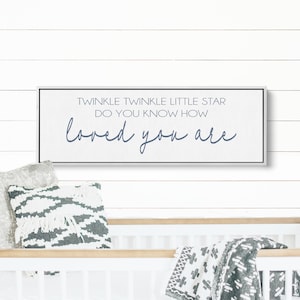 May include: A white wooden sign with black trim and a gray background. The sign reads "Twinkle Twinkle Little Star Do You Know How Loved You Are" in blue lettering.