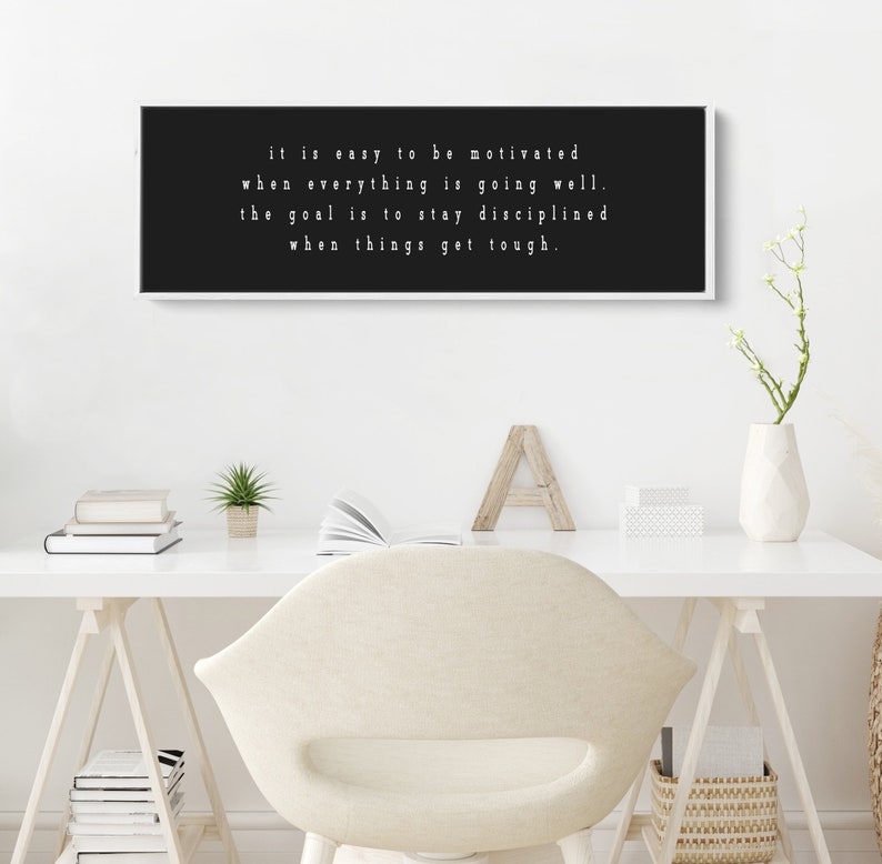 K&ouml;nnte beinhalten: Schwarzwei&szlig;es Motivationszitat auf einer gerahmten Leinwand. Das Zitat lautet: "Es ist leicht, motiviert zu sein, wenn alles gut l&auml;uft. Das Ziel ist es, diszipliniert zu bleiben, wenn es schwierig wird."