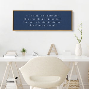 K&ouml;nnte beinhalten: Ein gerahmter Leinwanddruck in Marineblau mit wei&szlig;em Text, der lautet "it is easy to be motivated when everything is going well. the goal is to stay disciplined when things get tough."