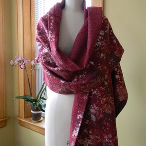 May include: A red and silver patterned scarf with a floral design. The scarf is draped over a white dress form.