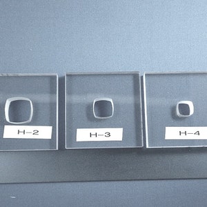 May include: Three clear glass squares with a silver ring inside each. The rings are different sizes. The squares are labeled H-2, H-3, and H-4.